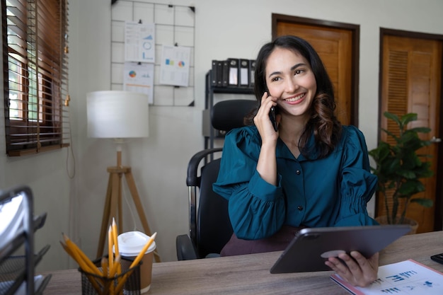 Portret van jonge Aziatische zakenvrouw praten op smartphone schrijven notebook laptop in kantoor aan huis mooi meisje op bureau computer take home order Startup business Azië vrouw online MKB telemarketing