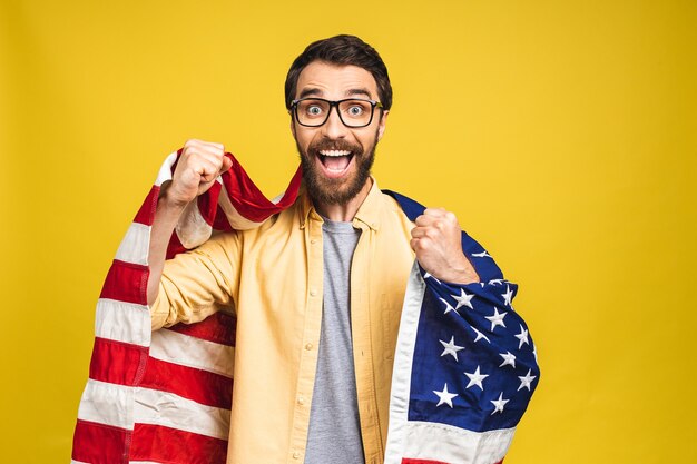 Portret van jonge, bebaarde gelukkige man met een Amerikaanse vlag van de V.s. geïsoleerd op gele achtergrond.