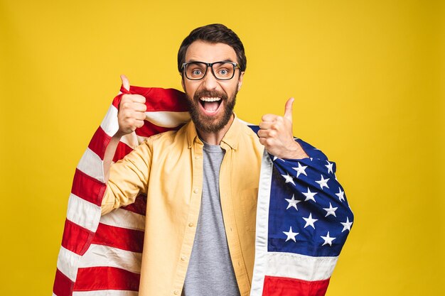 Portret van jonge, bebaarde gelukkige man met een Amerikaanse vlag van de V.s. geïsoleerd op gele achtergrond.