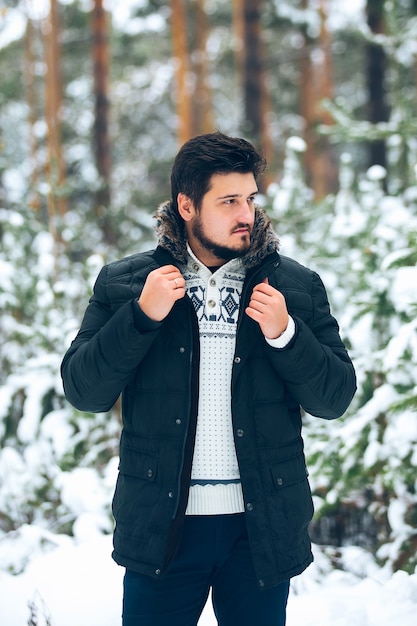 Portret van jonge bebaarde mannen in het bos in de winter, donsjack