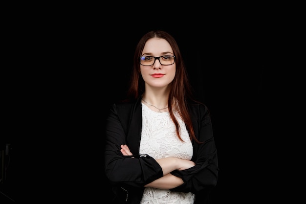 Portret van jonge bedrijfsvrouw met bril in een zwarte jas op zwart.