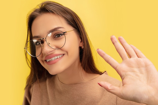 Foto portret van jonge blanke vrouw met heldere emoties geïsoleerd op gele studio achtergrond