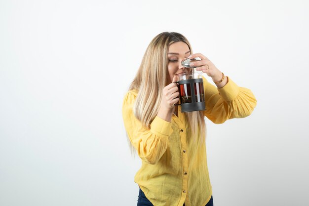 Portret van jonge blonde vrouw het drinken van thee uit theepot