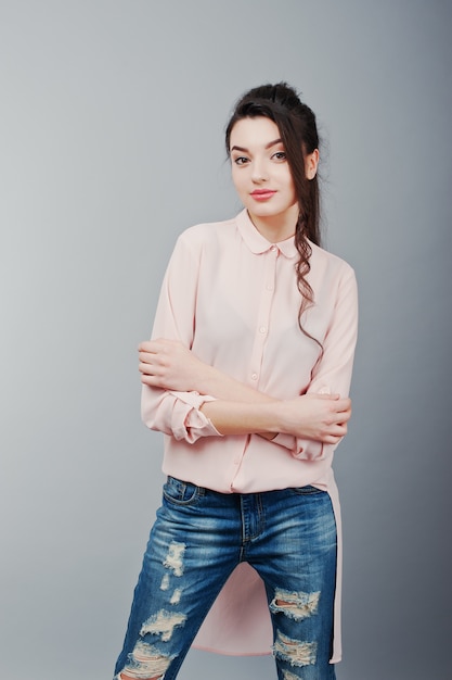 Portret van jonge brunette meisje draagt in roze blouse, gescheurde spijkerbroek