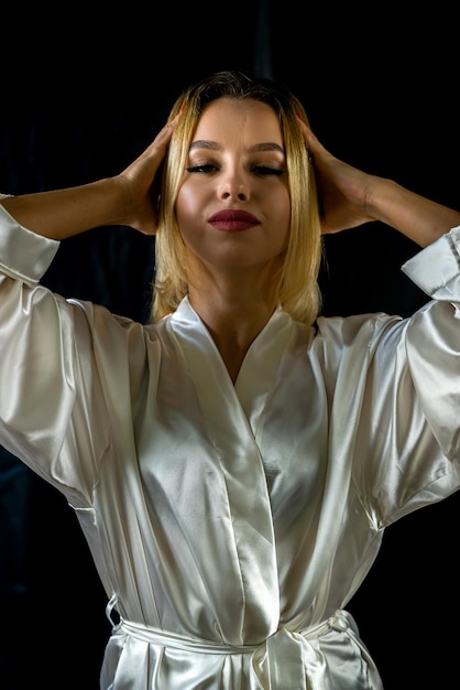 Portret van jonge charmante vrouw in zijden gewaad op houten studiostoel poseren geïsoleerd op groene achtergrond concept van een portret van een mooi meisje