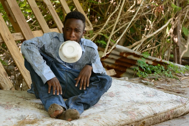 Portret van jonge dakloze Afrikaanse man in de straten buitenshuis