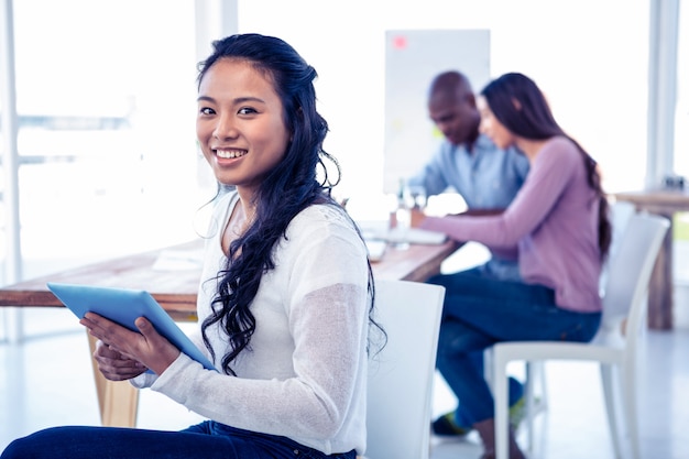 Portret van jonge de tabletpc van de onderneemsterholding met collega&#39;s op creatief kantoor