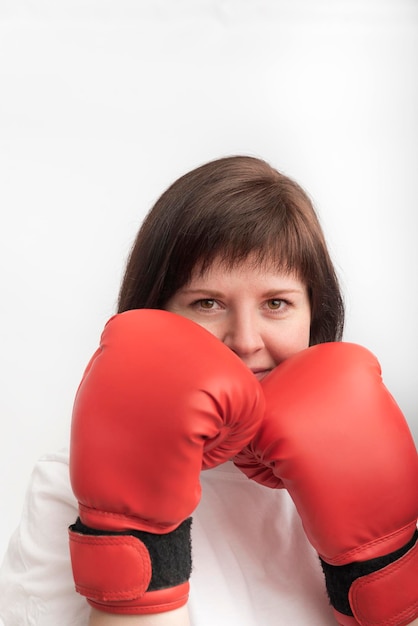 Portret van jonge donkerharige vrouw in rode bokshandschoenen. Vrouw bokser op witte achtergrond. Verticaal kader