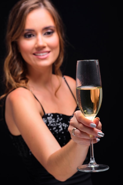 Portret van jonge elegante vrouw het drinken champagne tegen zwarte