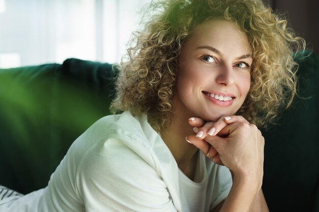 Portret van jonge en mooie vrouw met krullend haar die op groene bank liggen