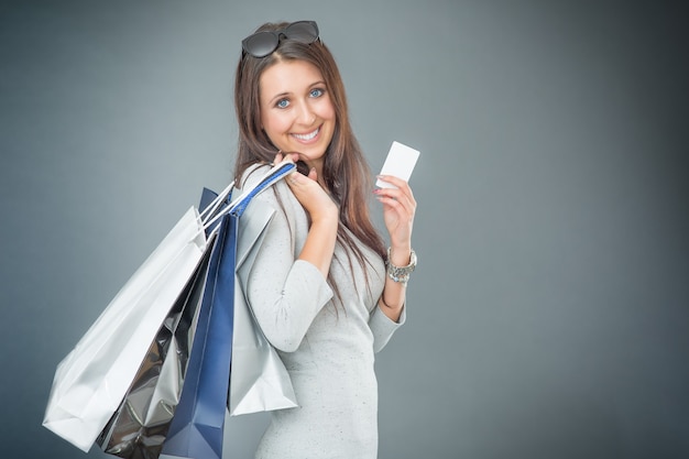 Portret van jonge gelukkig lachende vrouw met boodschappentassen creditcard en schoenen.