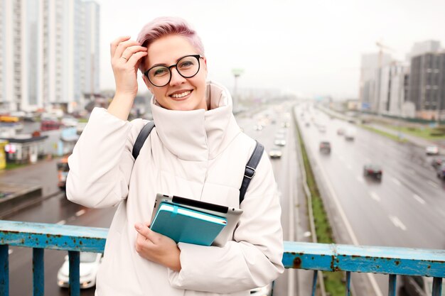 Portret van jonge gelukkige blogger met moderne laptop en voorbeeldenboeken buitenshuis