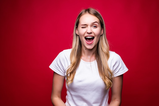 Portret van jonge gelukkige vrouw die over rode muur wordt geïsoleerd