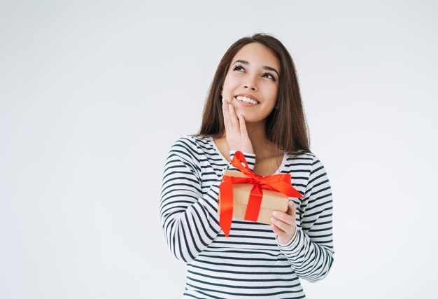 Portret van jonge glimlachende Aziatische vrouw met giftdoos in handen op witte geïsoleerde achtergrond