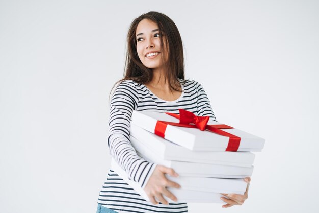 Portret van jonge glimlachende Aziatische vrouw met stapel geschenkdozen in handen op witte geïsoleerde achtergrond