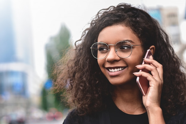 Portret van jonge glimlachende vrouw die op de telefoon spreekt