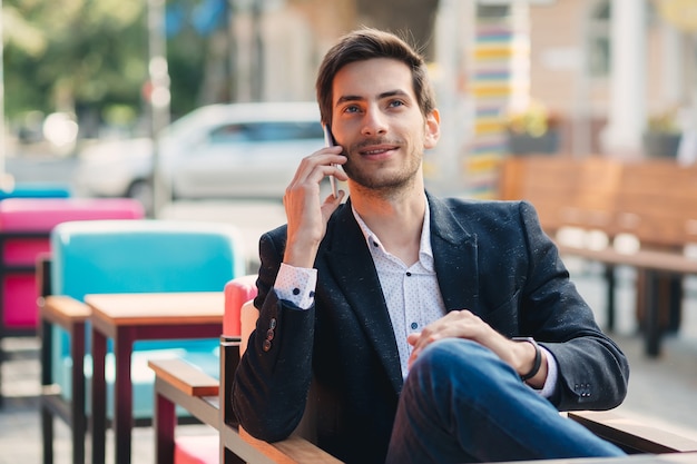 Portret van jonge glimlachende zakenman die op de telefoon spreekt