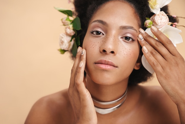 Portret van jonge halfnaakte sproeten Afro-Amerikaanse vrouw met bloemen in haar haar