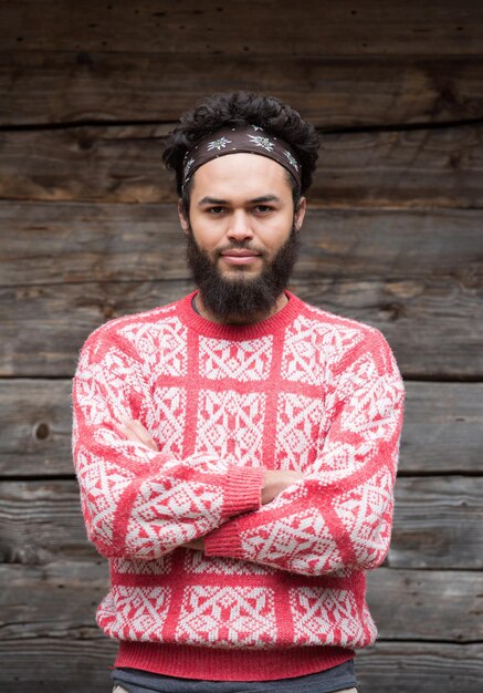 Foto portret van jonge hipster, man met baard voor oud vintage houten huis