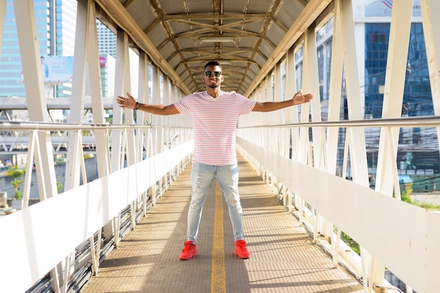 Portret van jonge knappe Afrikaanse bebaarde man met Afro haar op de loopbrug in de stad buiten