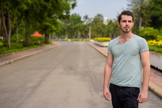 Portret van jonge knappe bebaarde man ontspannen in het park buitenshuis