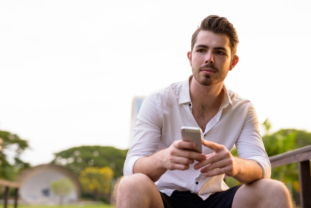 Portret van jonge knappe bebaarde man ontspannen in het park buitenshuis