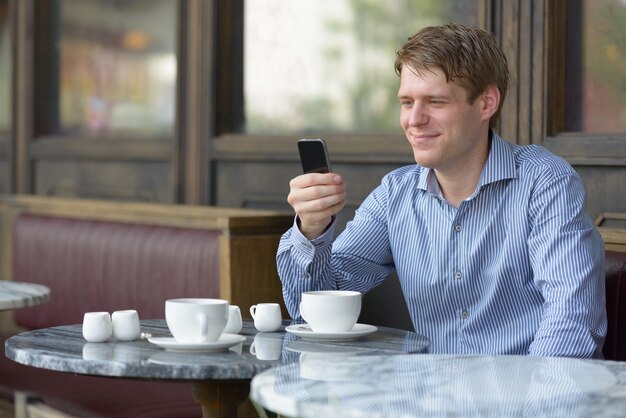 Portret van jonge knappe blonde zakenman ontspannen in de coffeeshop buitenshuis