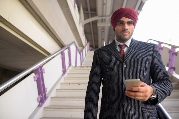 Portret van jonge knappe Indiase Sikh zakenman tulband dragen tijdens het verkennen van de stad Bangkok, Thailand