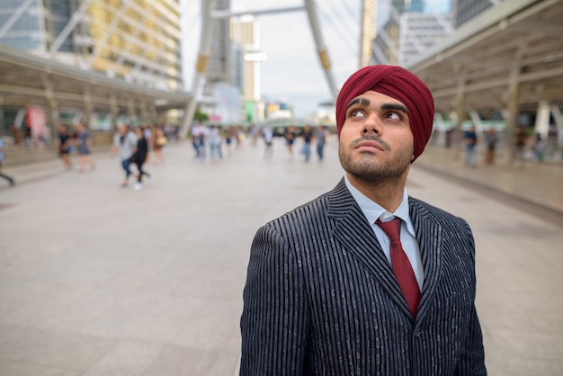 Portret van jonge knappe Indiase Sikh zakenman tulband dragen tijdens het verkennen van de stad Bangkok, Thailand