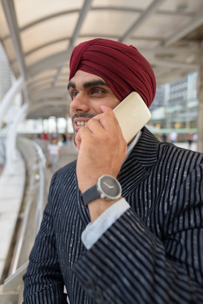 Portret van jonge knappe Indiase Sikh zakenman tulband dragen tijdens het verkennen van de stad Bangkok, Thailand