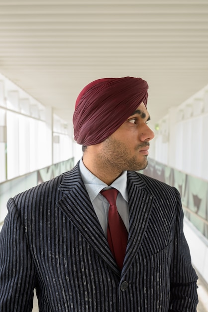 Foto portret van jonge knappe indiase sikh zakenman tulband dragen tijdens het verkennen van de stad bangkok, thailand