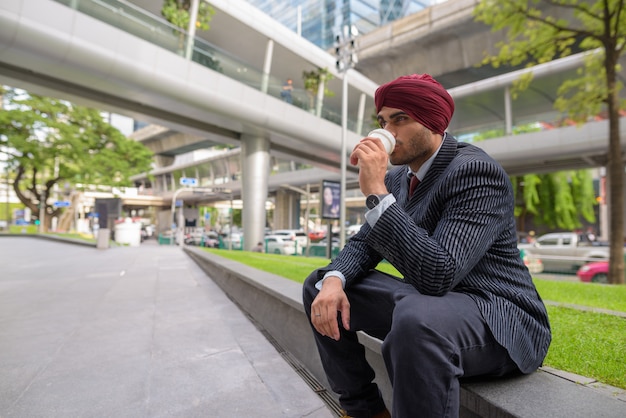 Portret van jonge knappe indiase sikh zakenman tulband dragen tijdens het verkennen van de stad bangkok, thailand