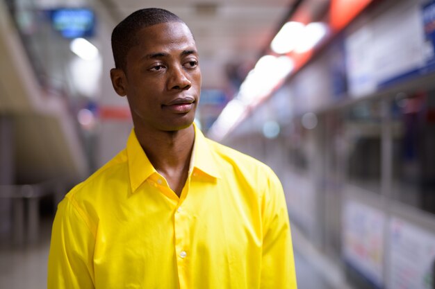 Portret van jonge knappe kale Afrikaanse zakenman in het metrostation