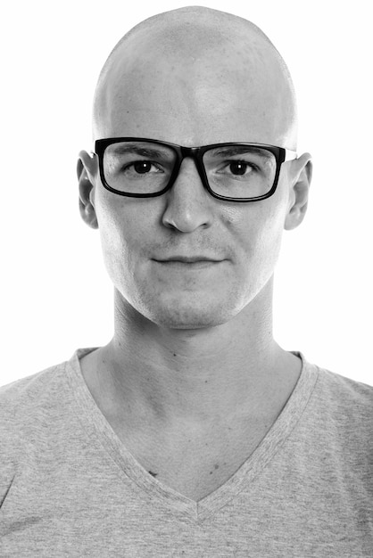 Portret van jonge knappe kale nerd man met bril geïsoleerd op wit in zwart-wit