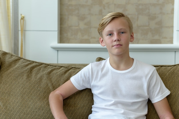 Portret van jonge knappe Scandinavische jongen met blond haar in de huiskamer