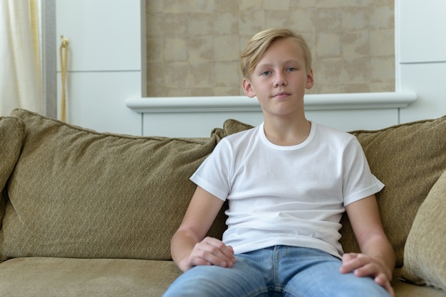 Portret van jonge knappe Scandinavische jongen met blond haar in de huiskamer