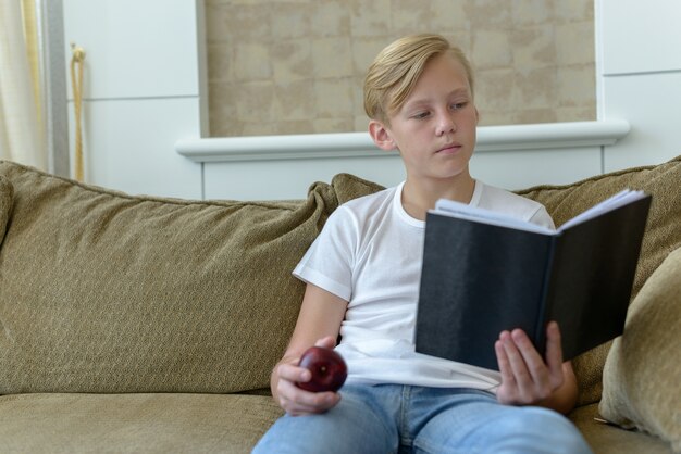 Portret van jonge knappe Scandinavische jongen met blond haar in de huiskamer