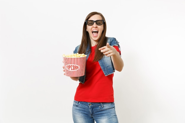 Portret van jonge lachen mooie vrouw in 3d imax bril kijken naar film film, emmer popcorn houden en wijsvinger wijzen op camera geïsoleerd op een witte achtergrond. emoties in bioscoopconcept.