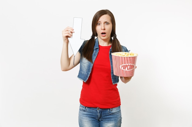 Portret van jonge lachende vrouw in casual kleding kijken naar film film, emmer popcorn vasthouden, witte pijl omhoog op copyspace geïsoleerd op een witte achtergrond. Emoties in bioscoopconcept.