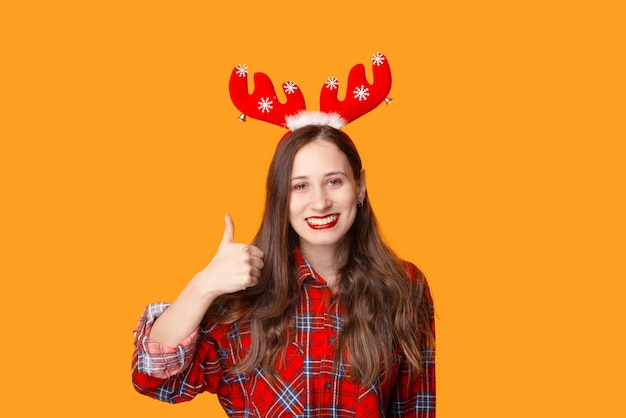 Portret van jonge lachende vrouw klaar voor kerstvakantie en duim opdagen