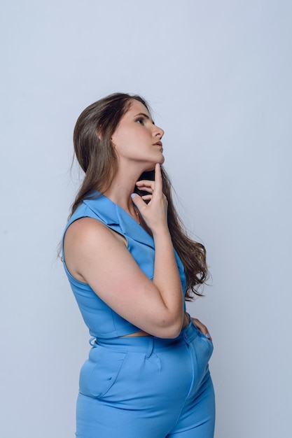 portret van jonge Latijnse vrouw in blauw poseert met hand op kin studio schot kopie ruimte
