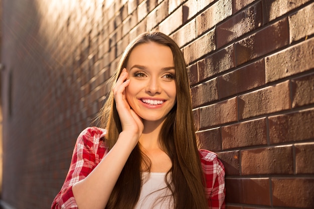 Portret van jonge leuke vrouw dichtbij bakstenen muur