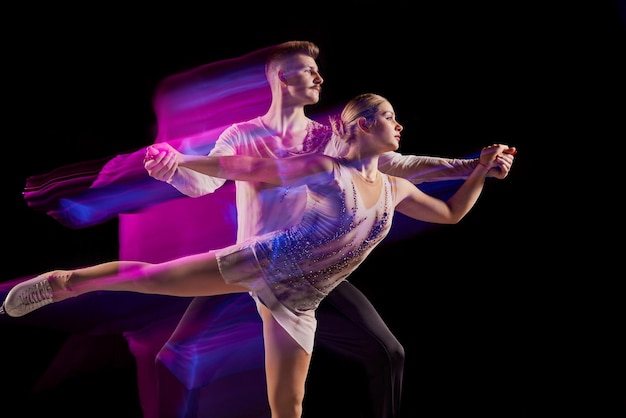 Portret van jonge man en vrouw kunstschaatsen atleten dansen geïsoleerd op zwarte achtergrond in