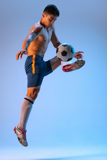 Portret van jonge man professionele voetballer opleiding geïsoleerd over blauwe studio achtergrond in