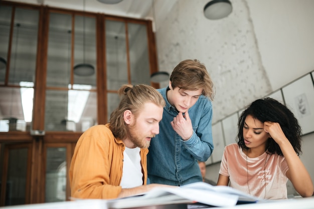 Portret van jonge mensen die bedachtzaam iets in bureau bespreken