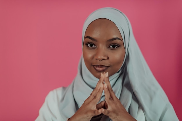 Portret van jonge moderne moslimschoonheid die traditionele islamitische kleding draagt op plastic roze achtergrond. Selectieve aandacht. Foto van hoge kwaliteit