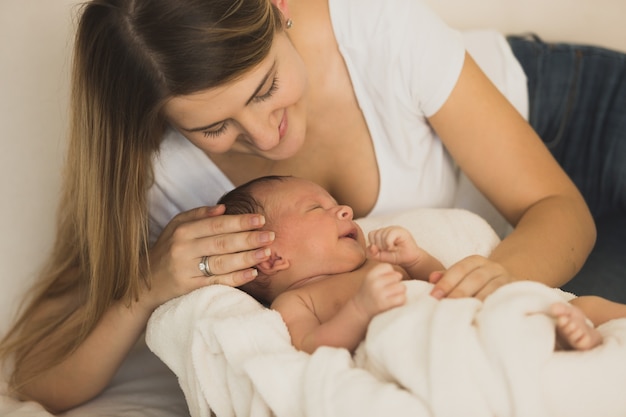 Portret van jonge moeder poseren met babyjongen op bed