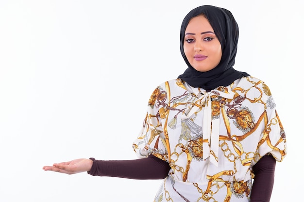 Portret van jonge mooie Afrikaanse moslimvrouw die hijab draagt die tegen witte muur wordt geïsoleerd