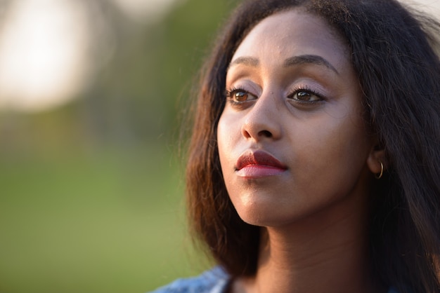 Portret van jonge mooie Afrikaanse vrouw ontspannen in het park buiten