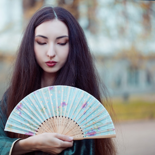 Portret van jonge mooie Aziaten in grijze kimono en met een ventilator